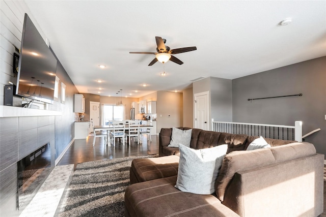 living room with dark hardwood / wood-style floors, ceiling fan, and a tile fireplace