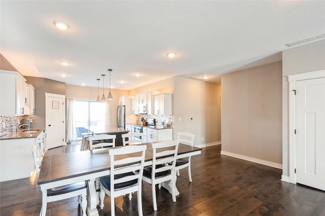 dining area with sink, a textured ceiling, and dark hardwood / wood-style floors