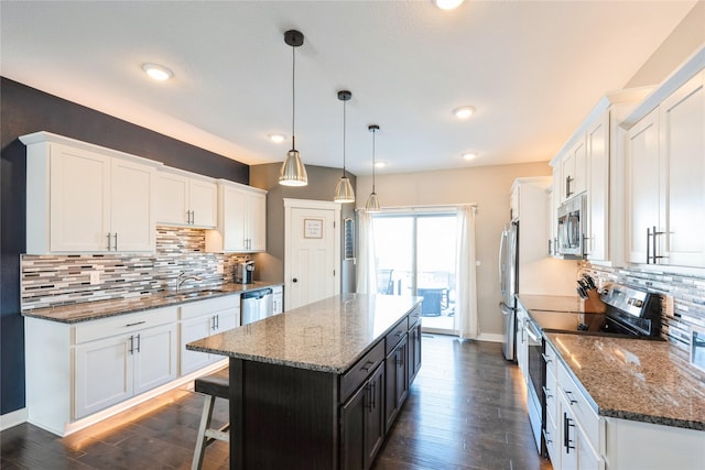 kitchen with pendant lighting, a center island, white cabinetry, stainless steel appliances, and tasteful backsplash