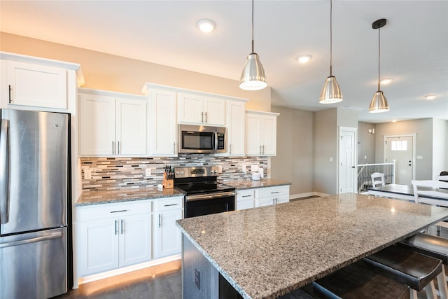 kitchen featuring light stone countertops, white cabinets, decorative light fixtures, backsplash, and stainless steel appliances