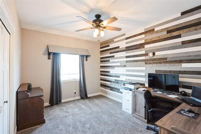 carpeted home office featuring ceiling fan and wood walls