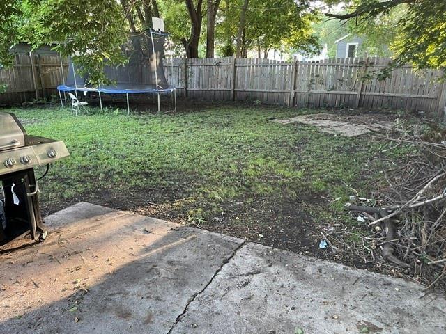 view of yard with a trampoline and a patio