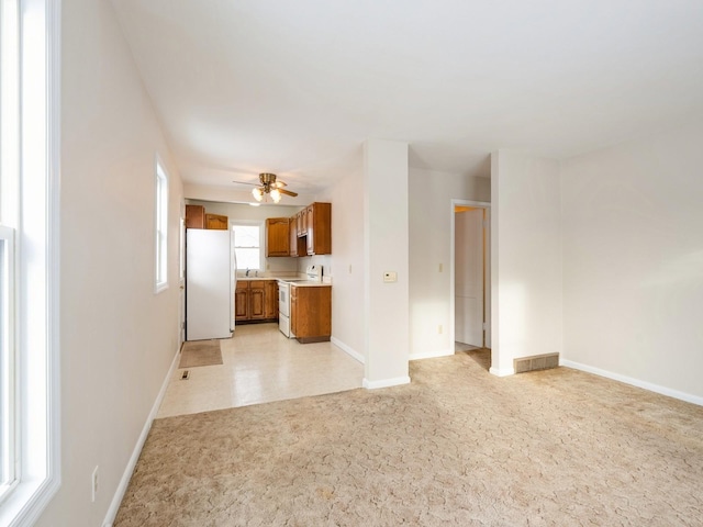 unfurnished living room featuring ceiling fan, sink, and light colored carpet