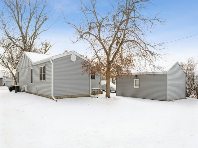 snow covered back of property featuring central air condition unit