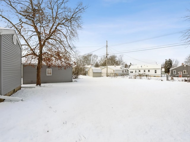 yard covered in snow with a storage shed