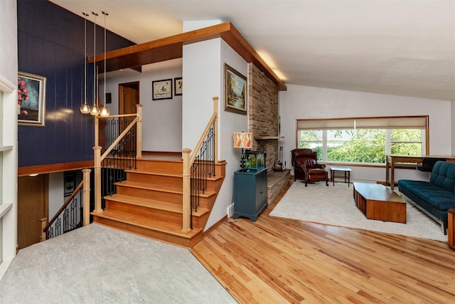 staircase featuring a stone fireplace, hardwood / wood-style floors, and high vaulted ceiling