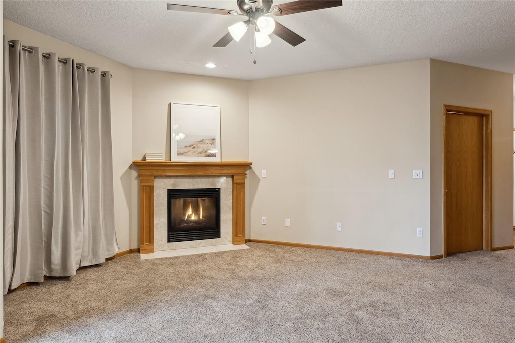 unfurnished living room with carpet flooring, a textured ceiling, ceiling fan, and a tiled fireplace