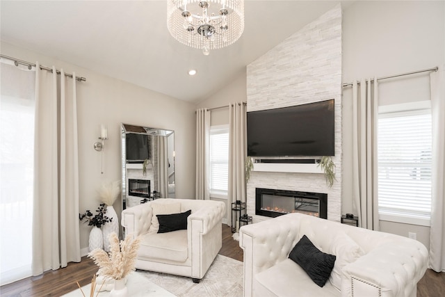 living room featuring an inviting chandelier, a stone fireplace, lofted ceiling, and hardwood / wood-style flooring