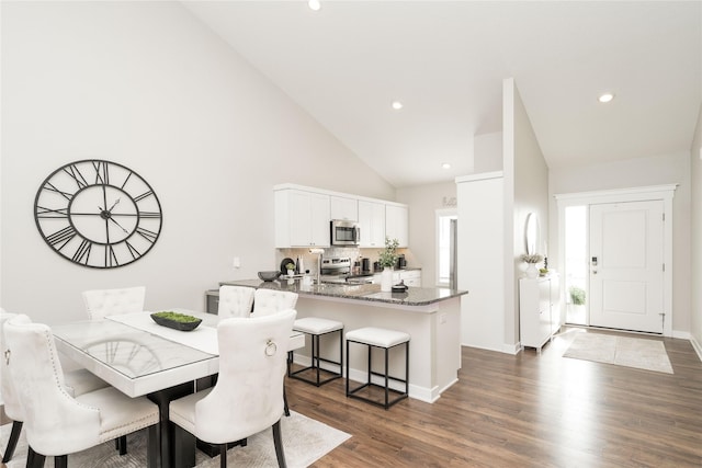 dining area featuring dark hardwood / wood-style flooring and high vaulted ceiling