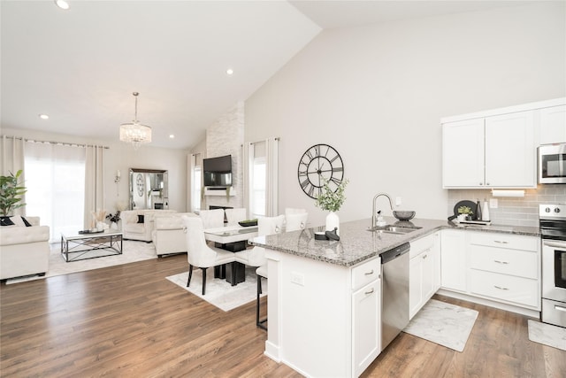 kitchen featuring stainless steel appliances, white cabinetry, hanging light fixtures, and sink