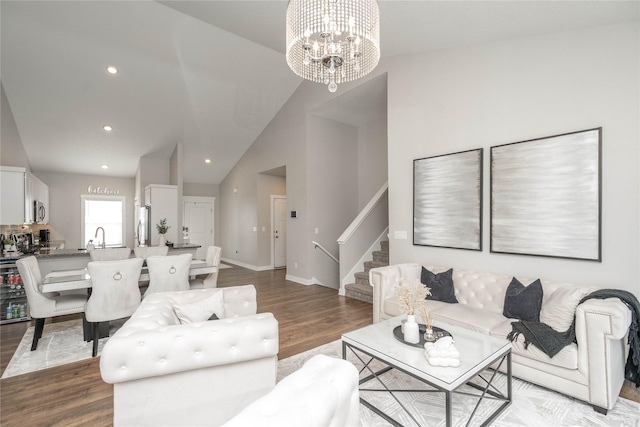 living room with an inviting chandelier, high vaulted ceiling, and light hardwood / wood-style flooring