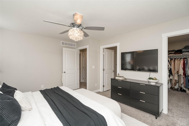 bedroom with a walk in closet, light colored carpet, a closet, and ceiling fan