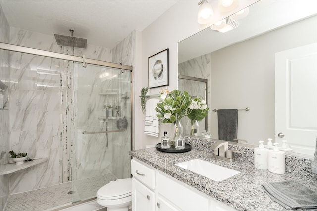 bathroom featuring a shower with door, vanity, and toilet