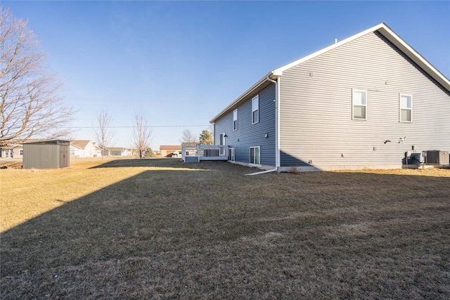 view of side of home featuring a shed, cooling unit, a lawn, and a deck