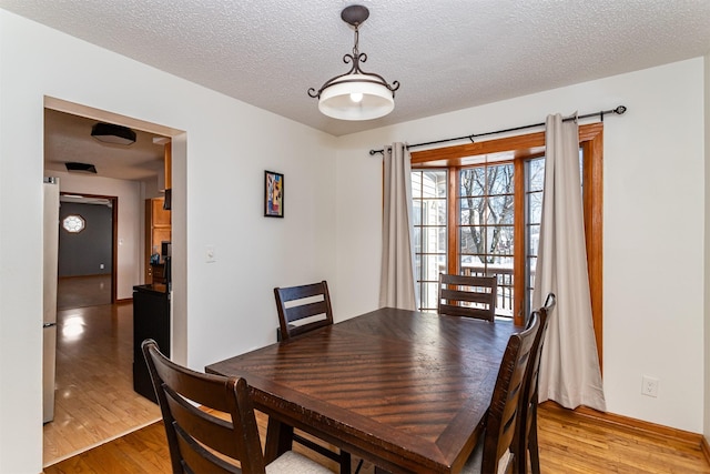 dining space with light hardwood / wood-style flooring and a textured ceiling