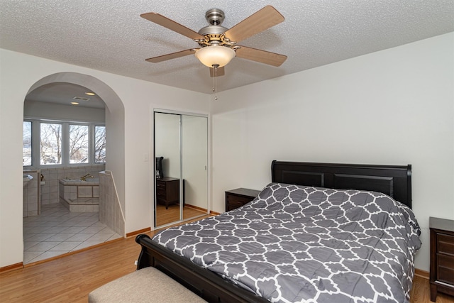 bedroom featuring wood-type flooring, ceiling fan, a textured ceiling, and a closet