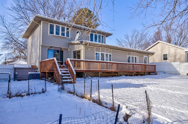 snow covered back of property featuring a jacuzzi and a deck