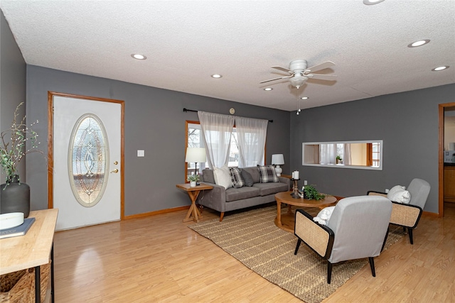 living room featuring ceiling fan, recessed lighting, light wood-type flooring, and a textured ceiling