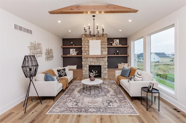 living room featuring beamed ceiling, light wood-type flooring, a notable chandelier, and a fireplace