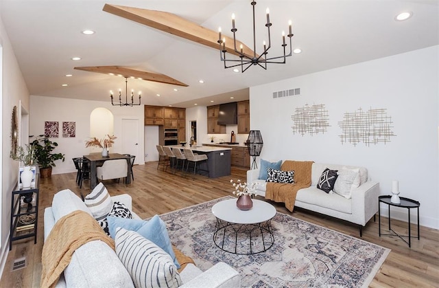 living room with wood-type flooring, sink, a chandelier, and lofted ceiling with beams