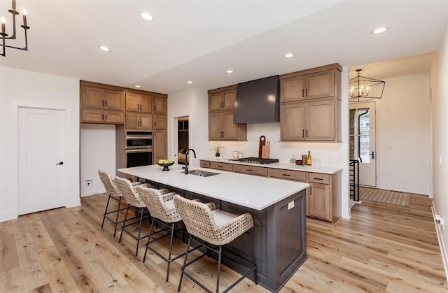 kitchen featuring sink, a breakfast bar, a center island with sink, custom exhaust hood, and a chandelier