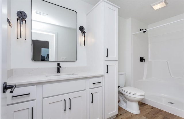 bathroom featuring vanity, hardwood / wood-style floors, toilet, and walk in shower