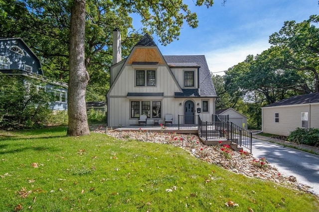 back of property featuring an outdoor structure, a garage, and a yard