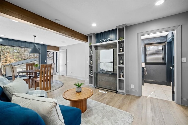 living room featuring beam ceiling, built in features, and light hardwood / wood-style flooring