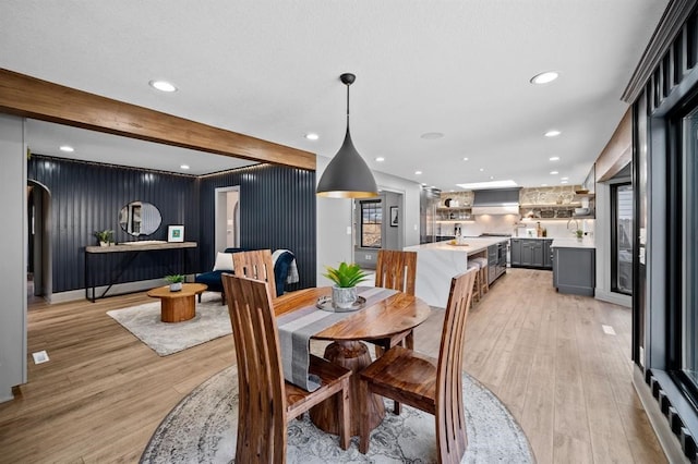 dining room with beamed ceiling and light hardwood / wood-style floors