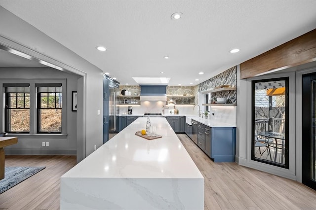 kitchen featuring light stone counters, dishwasher, light hardwood / wood-style floors, and sink