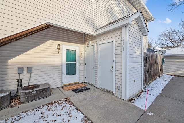 snow covered property entrance featuring central AC unit