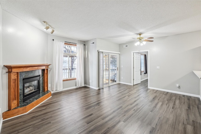 unfurnished living room featuring dark hardwood / wood-style floors, ceiling fan, a textured ceiling, and a tiled fireplace