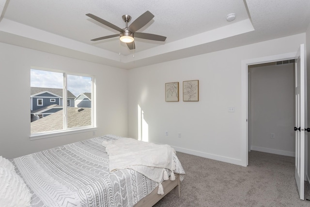 carpeted bedroom featuring ceiling fan and a tray ceiling