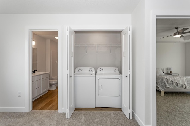 laundry room with light colored carpet, ceiling fan, washer and clothes dryer, and sink