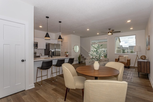 dining room with sink, dark hardwood / wood-style flooring, a textured ceiling, and ceiling fan