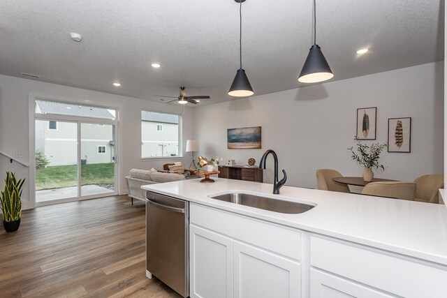 kitchen with a textured ceiling, dishwasher, hanging light fixtures, white cabinetry, and sink