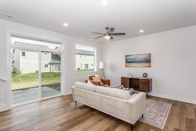 living room with a textured ceiling, ceiling fan, and light hardwood / wood-style floors