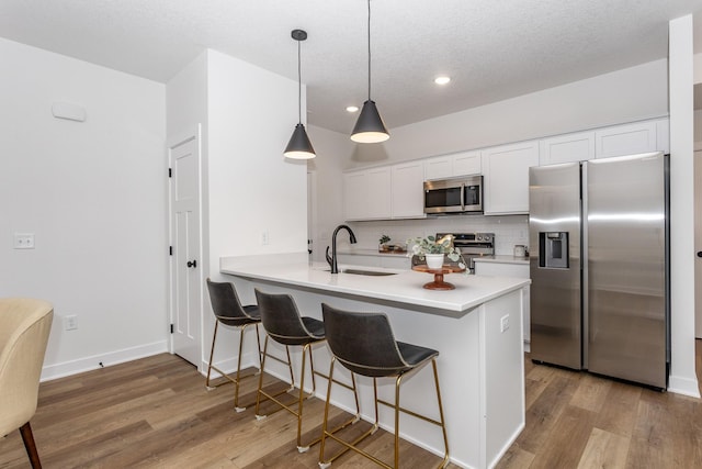 kitchen featuring kitchen peninsula, stainless steel appliances, white cabinets, and sink