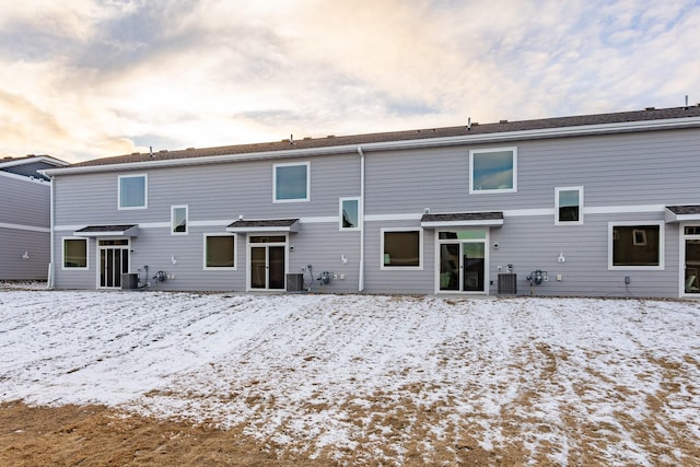 snow covered back of property with central AC