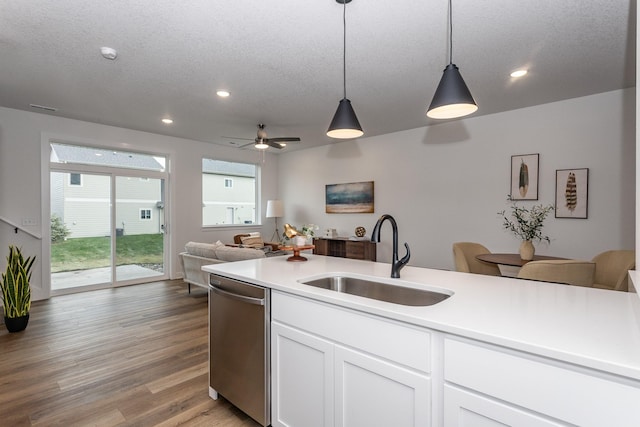 kitchen featuring a textured ceiling, sink, white cabinetry, decorative light fixtures, and stainless steel dishwasher