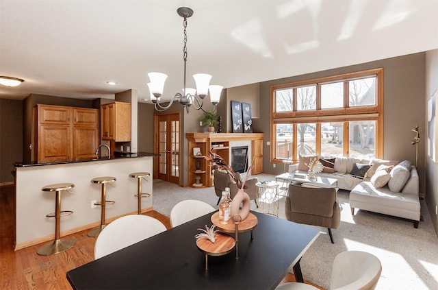 dining room with a glass covered fireplace, baseboards, light wood finished floors, and an inviting chandelier