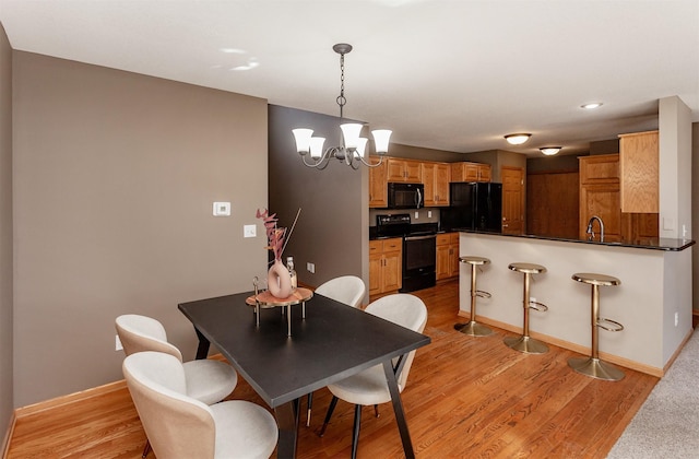 dining space with a chandelier, light wood-style flooring, and baseboards