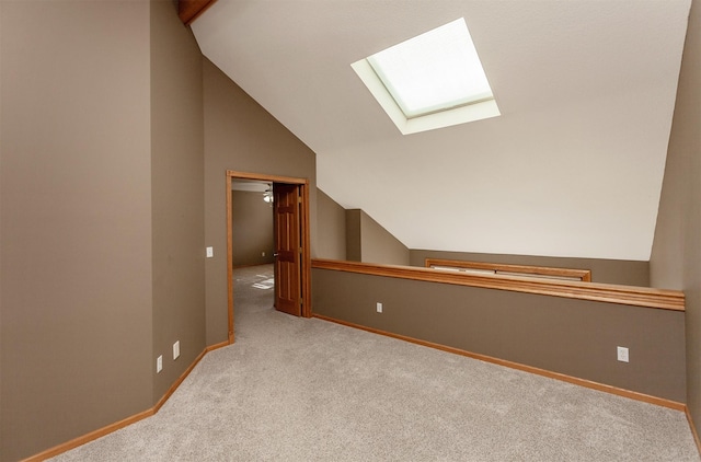 bonus room featuring lofted ceiling with skylight, light carpet, and baseboards