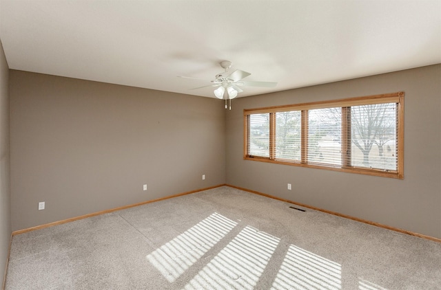 empty room with light colored carpet, visible vents, ceiling fan, and baseboards