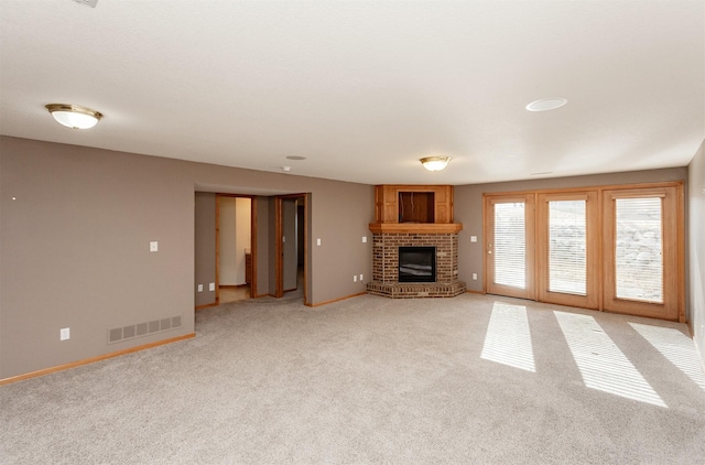 unfurnished living room featuring light carpet, baseboards, a fireplace, and visible vents