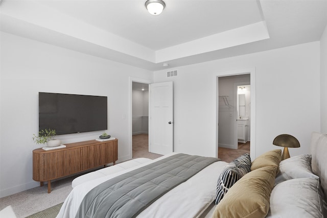 carpeted bedroom with a raised ceiling, a closet, a spacious closet, and connected bathroom