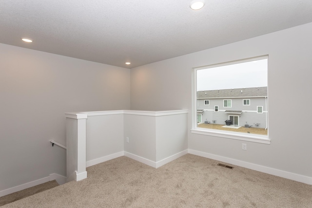 unfurnished room with light carpet, baseboards, visible vents, a textured ceiling, and recessed lighting