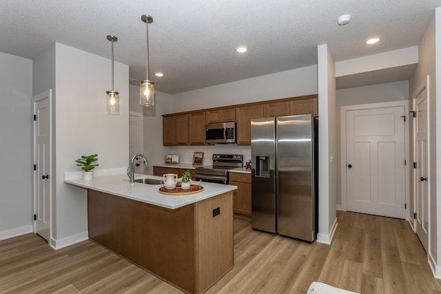 kitchen featuring stainless steel appliances, a peninsula, a sink, light countertops, and brown cabinets