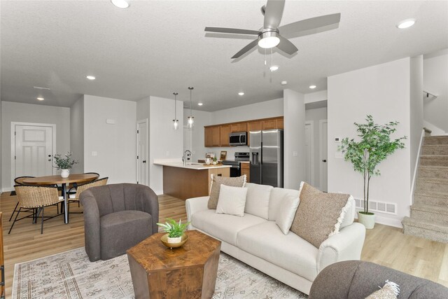 234 NW Waverly Dr, Waukee, IA 50263 - living room with light wood-style floors, stairway, ceiling fan, baseboards, and recessed lighting