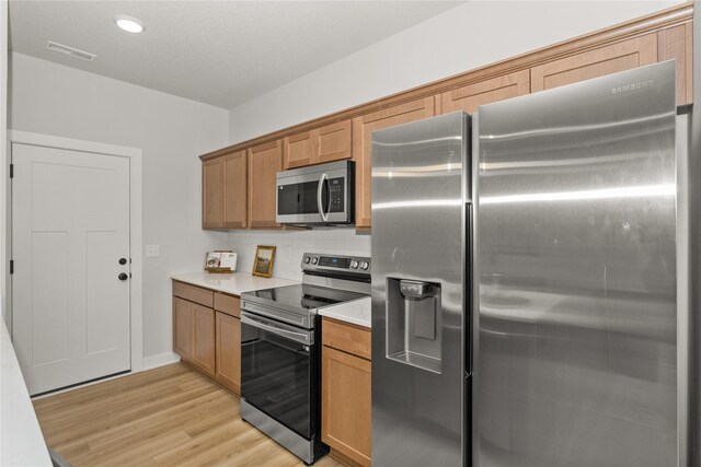 234 NW Waverly Dr, Waukee, IA 50263 - kitchen featuring stainless steel appliances, light wood finished floors, light countertops, tasteful backsplash, and brown cabinetry